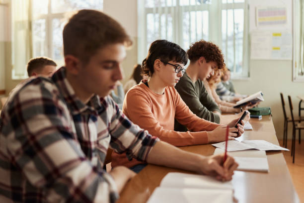 istock Female high school student using cell phone on a class at school. 1690369808