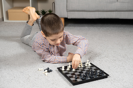Little boy playing chess. Board games for children.
