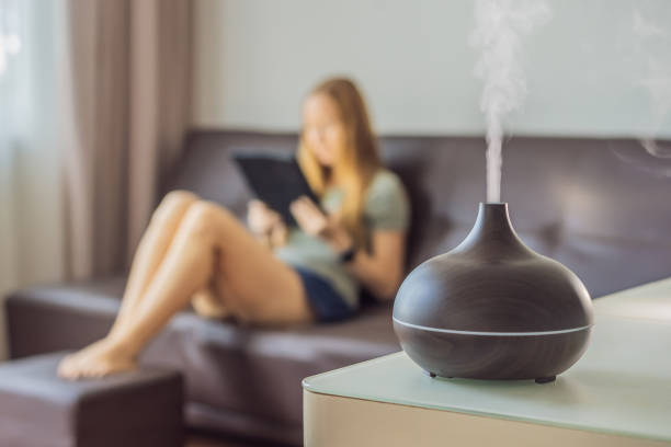 istock Aromatherapy Concept. Wooden Electric Ultrasonic Essential Oil Aroma Diffuser and Humidifier. Ultrasonic aroma diffuser for home. Woman resting at home 1690378962