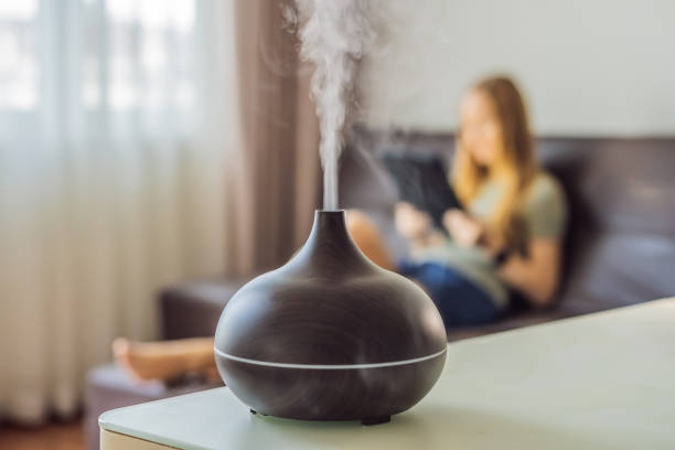 istock Aromatherapy Concept. Wooden Electric Ultrasonic Essential Oil Aroma Diffuser and Humidifier. Ultrasonic aroma diffuser for home. Woman resting at home 1690379021