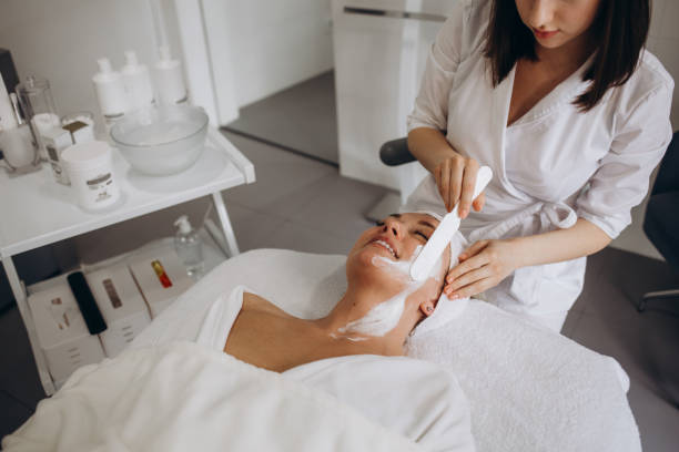 istock Cosmetologist applying mask on woman's face in beauty salon 1690380276