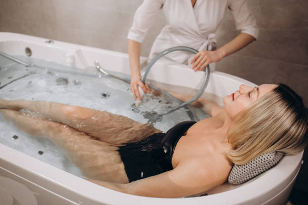 istock Pleases spa centre employee putting a flexible pipe into water in a bath with a client for hydromassage 1690380525