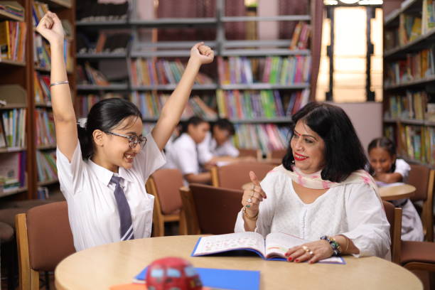 istock Confident school teacher teaching, educating  girl child student in library, excitement, hands up, yay, clapping. 1690387097