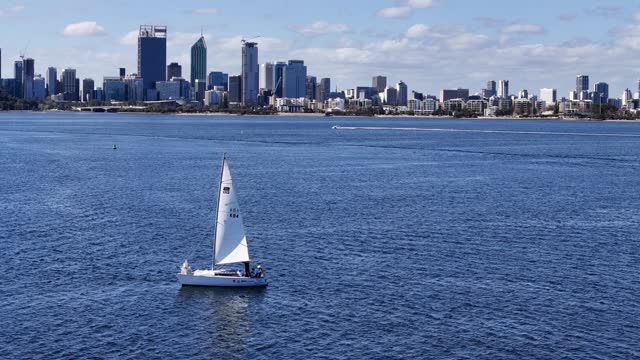 Sailing yacht with Perth city skyline in the background along the waters of Swan River