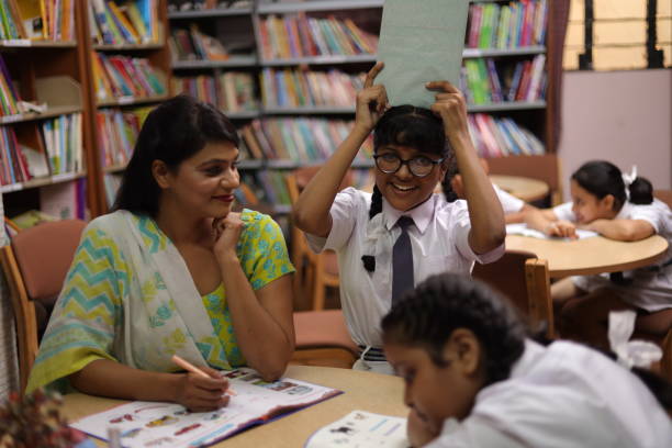 istock School teacher teaching one student and four students sleeping in library, nerd, topper, extra classes. 1690397908
