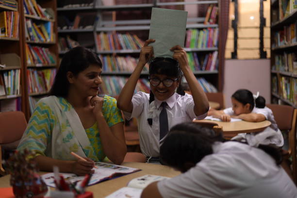 istock School teacher teaching one student and four students sleeping in library, nerd, topper, extra classes. 1690397911