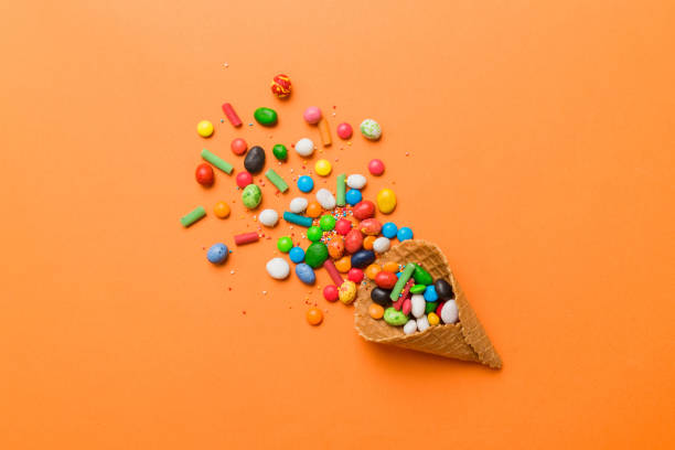 istock waffle cone full of assorted traditional candies falling out on colored background with copy space. Happy Holidays sale concept 1690408840