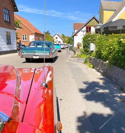 A procession of vintage automobiles gracefully cruises along a tranquil country road on the enchanting Samsø Island in Denmark. The photo was taken in Nordby, Denmark on September 9th 2023.