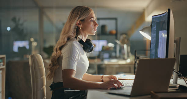 istock Night, business woman and designer on computer in office at table working on deadline. Creative, laptop and serious professional at desk focus on reading email, editing software or project in startup 1690409796