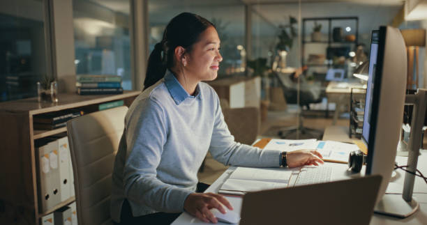istock Night, business woman and designer on computer in office at table working on deadline. Pc, creative and happy Asian professional at desk reading email, editing software and project in startup company 1690410861