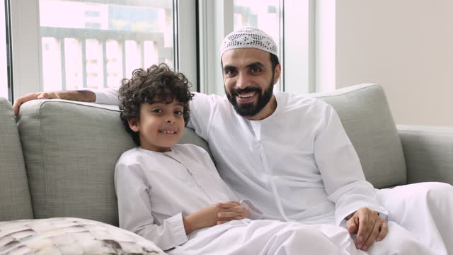Portrait of loving dad and son in traditional Muslim garments