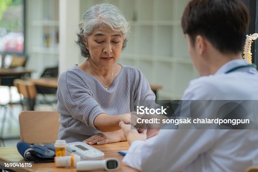 Senior Asian woman looking at the doctor and listening to her advice with trust and gratitude.