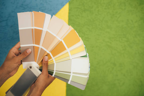 istock Woman choosing color using swatch catalog standing near wall. 1690491790