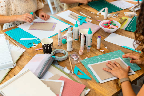 istock Scrapbook workshop. Women working on their album with glue and cutouts 1690493482