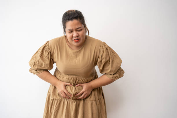 Young Asian plus size woman hand on stomach because nausea, painful disease feeling unwell, may develop gallstones or Cholecystitis. From gastritis and enteritis to people and health care concepts. mujer asiática joven de talla grande con la mano boca abajo porque las náuseas, la enfermedad dolorosa que se siente mal, puede desarrollar cálculos biliares o colecistitis. desde gastritis y enteritis hasta personas y conceptos de cuidado de la salud.