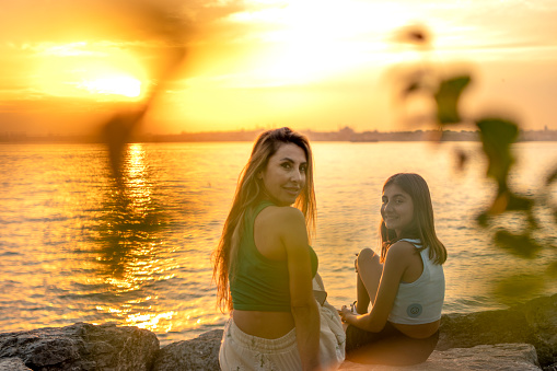 Woman and teenage girl relaxing at sunset time