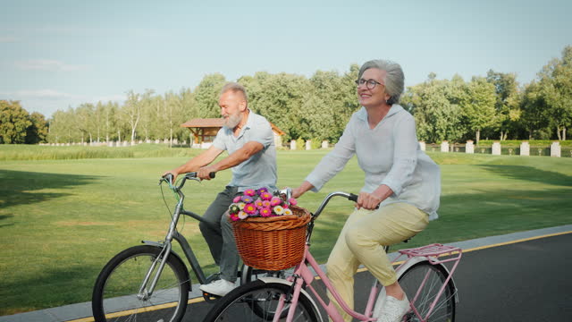 Aged husband and wife using bike for carefree riding at park
