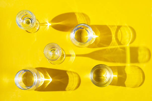 istock Various glasses with clear water stand on a yellow background, top view, flat lay. 1690593796
