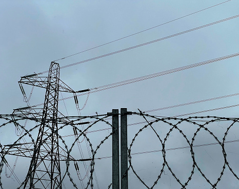 An overcast sky with pylon and barbed wire