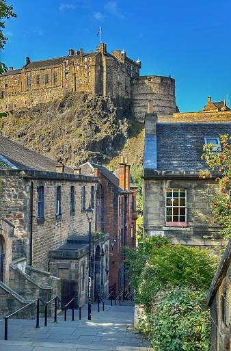Edinburgh, Scotland - People walking down the long staircase of The Vennel, with Edinburgh Castle on the horizon.