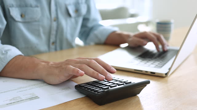 Unrecognizable man doing accountancy job using computer and calculator