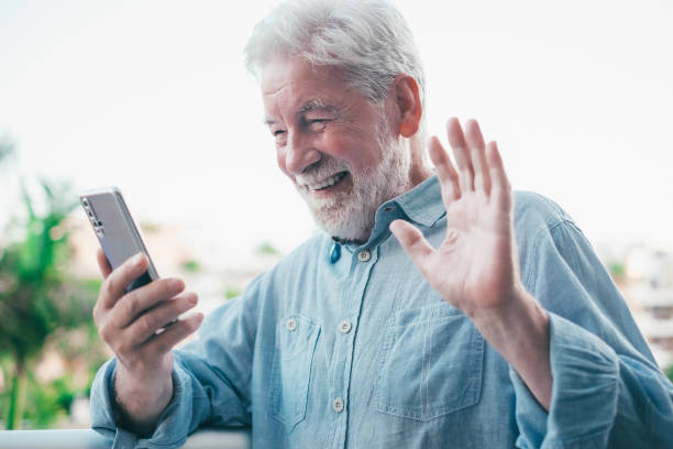 istock Video call concept. Handsome smiling bearded senior man talking on mobile phone using phone webcam to communicate in video chat 1690675612