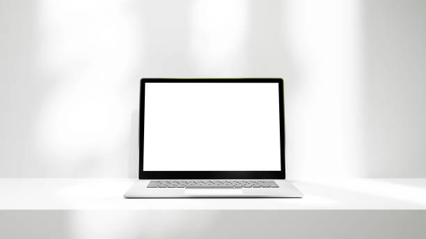 istock Laptop on white table platform with lights isolated, laptop white screen mock up empty blank space for design and advertisement 1690677939