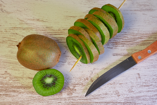 Closeup on ripe green kiwi fruits cut in slices on a wooden background. Healthy eating concept.