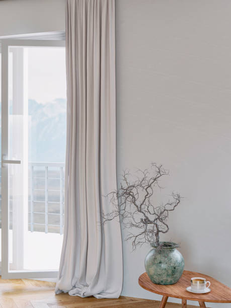 istock Empty interior with a low coffee table with decoration in front of a blank white wall background, an open window door with mountain view and long beige curtains 1690720339