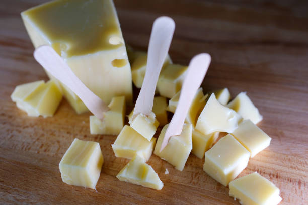 istock Female hands cutting cheese with a knife on a wooden cutting board. 1690768574