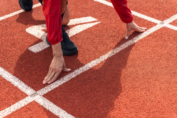 istock Close up runner man using starting block to start his run on running track background, outdoor workout concept, drink clear mineral water after jogging. Generation z lifestyle. 1690776812