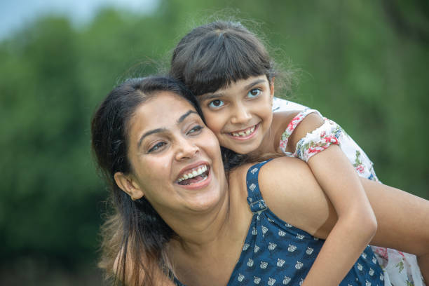 istock Mother piggybacking smiling daughter in park 1690781703