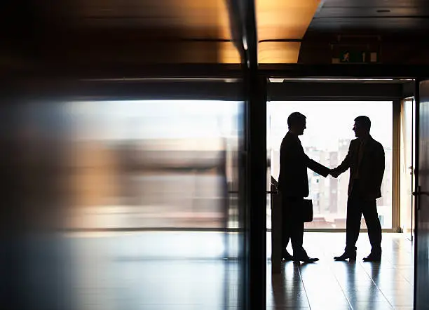 Photo of Businessmen shaking hands in corridor
