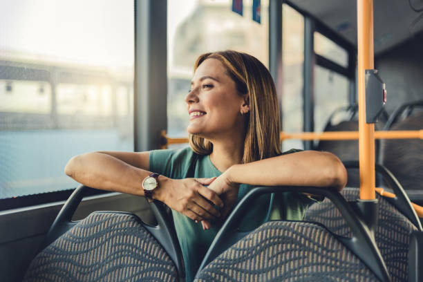 portrait of young satisfied woman traveling with public transport sitting relaxed. young woman riding in public transport. woman travelling by bus. - bus riding public transportation businessman imagens e fotografias de stock