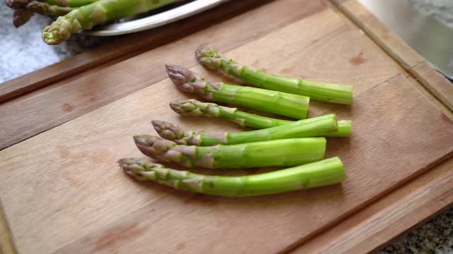 Asparagus spear-like vegetable (Asparagus officinalis) on wooden cutting board. Handheld