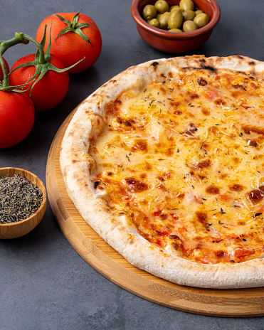Mozzarella cheese style pizza over stone background with tomatoes, olives and oregano.