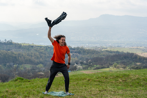 Young man throwing a jacket in the air on mountain