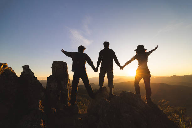 istock Silhuette Young group praying on the mountain, arms outstretched observing a beautiful dramatic sunrise. 1690828512