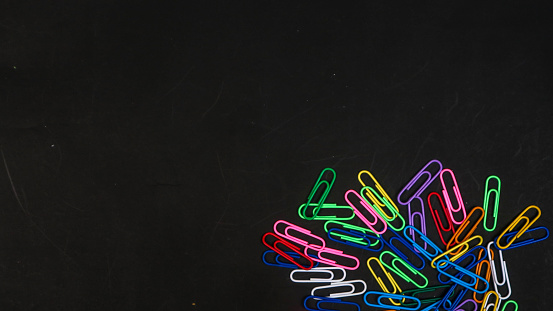 Colorful paper clips isolated on black background