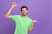 Photo of handsome young boyfriend directing fingers empty space presentation mockup price list tattoo salon isolated on violet background