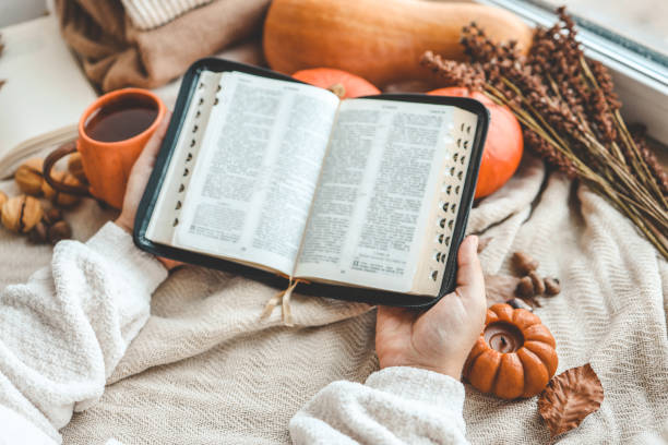 istock Open Bible in female hands in autumn interior 1690849837