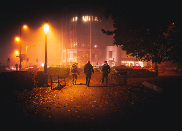 Brasov ,Romania-11/09/2022 . People walking on a dimly lit street on a foggy night