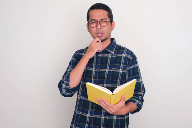 istock Adult Asian man thinking something with serious expression while holding a book 1690922499