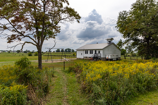 An Amish one room, schoolhouse in autumn. You can see the path through the grasses and late summer flowers that the children use to get to school.