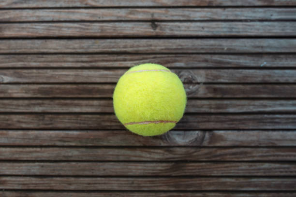 istock a tennis ball lying on wooden parquet 1690928443