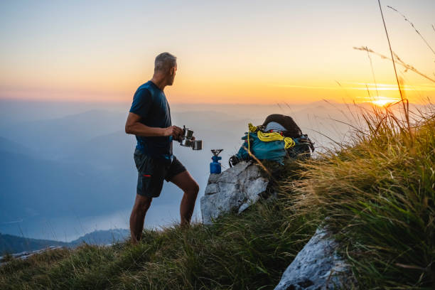 hiker preparing coffee with Italian coffee maker in the high mountains while the sun rises