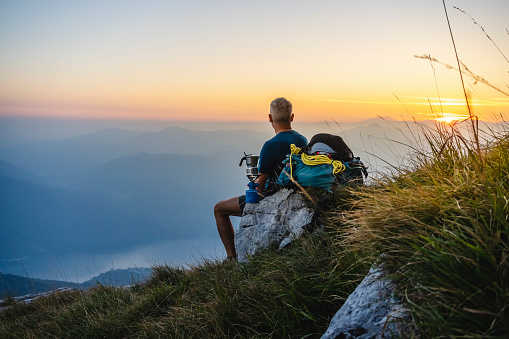 Hiker sitting high in the mountains relaxing and looking at the view during the sunrise