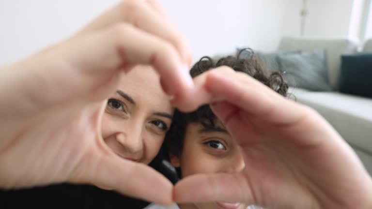 Loving Muslim mother and little son showing symbol of love