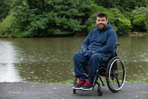 Portrait of a participant with a physical disability taking part in a fun run in Leazes Park in Newcastle upon Tyne in the North East of England. He is looking at the camera smiling.