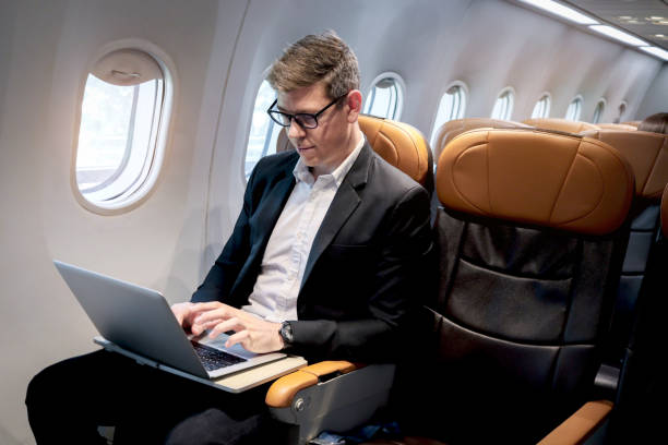 istock Busy businessman working on laptop computer during sitting in comfortable seat inside airplane, male passenger working in aircraft cabin during business trip, traveling with airline transportation. 1690937447